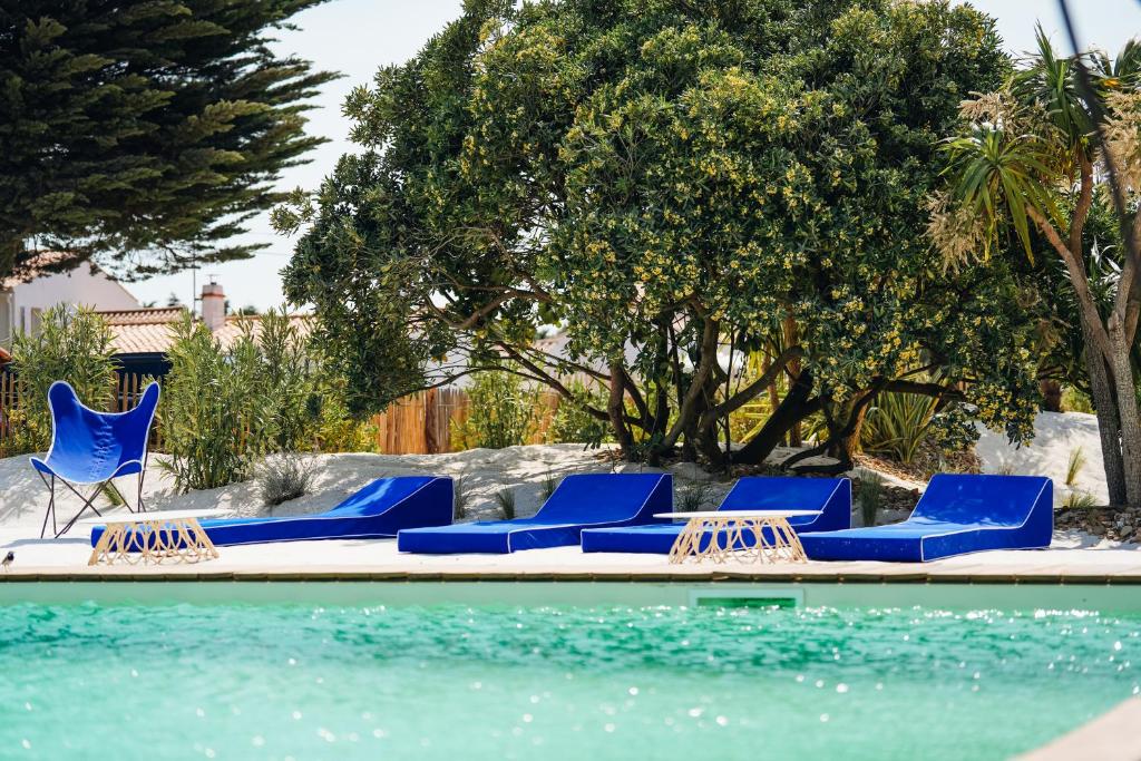 a group of blue lounge chairs next to a swimming pool at Hôtel Le Noirmoutier in Barbâtre