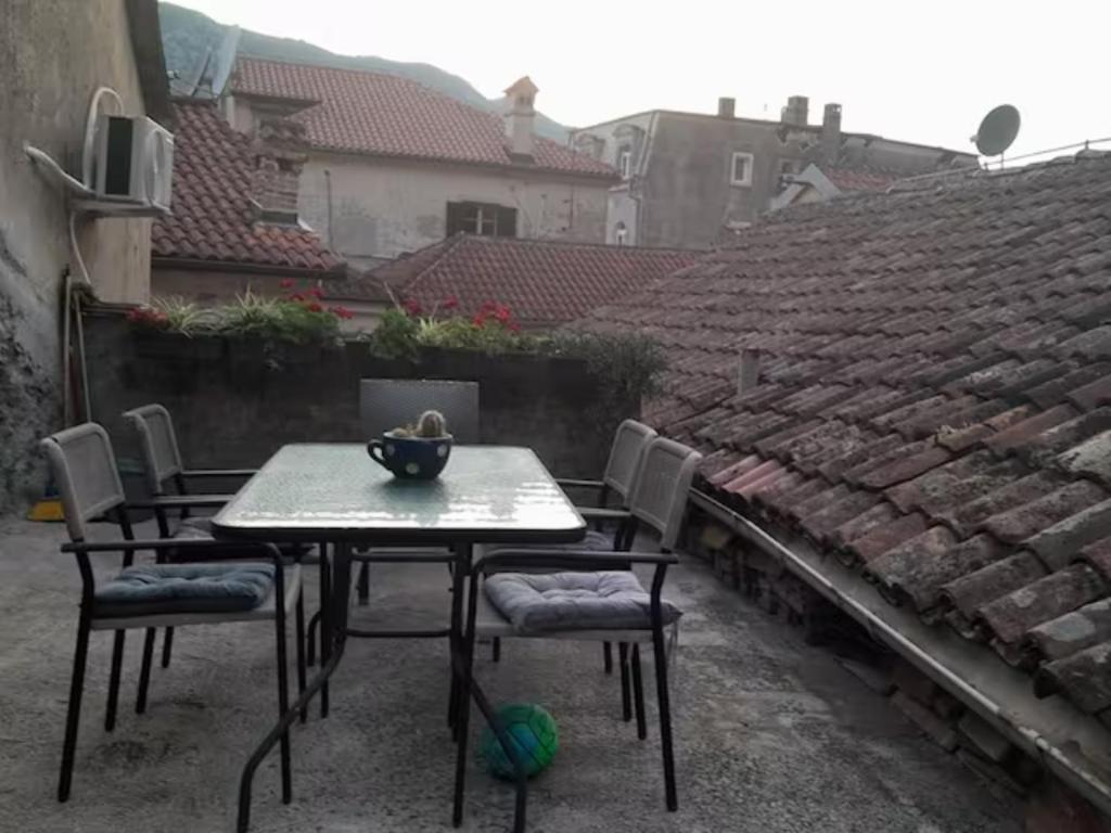 a table and chairs on a patio with a roof at Nada's room with terrace in Kotor