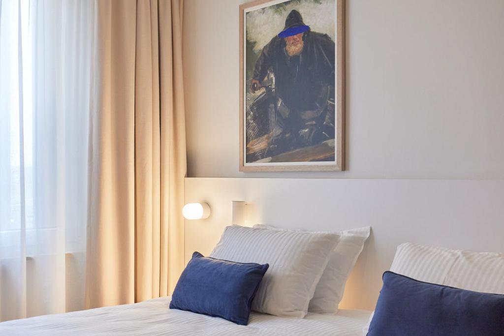 オーステンデにあるC-Hotels Burlingtonの壁に絵が飾られたベッドのある寝室