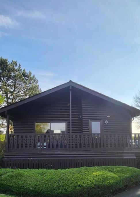 a log cabin with a fence in front of it at Hideaway Lodge in Carnforth