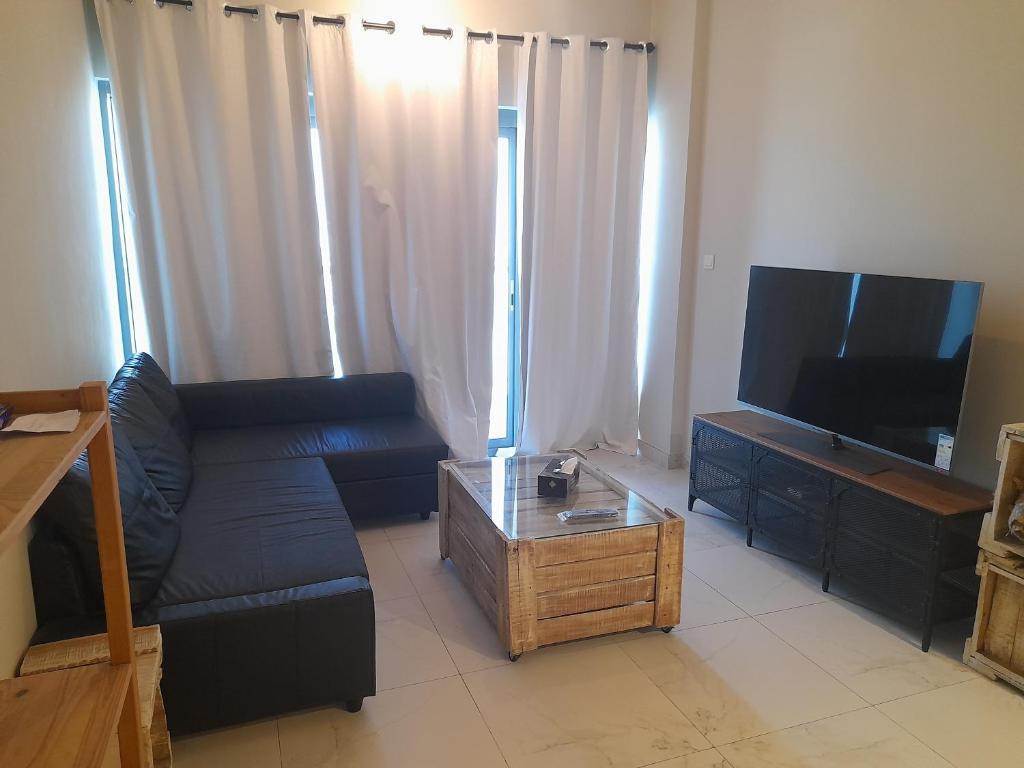 a chilled place في دبي: غرفة معيشة مع أريكة سوداء وتلفزيون بشاشة مسطحة