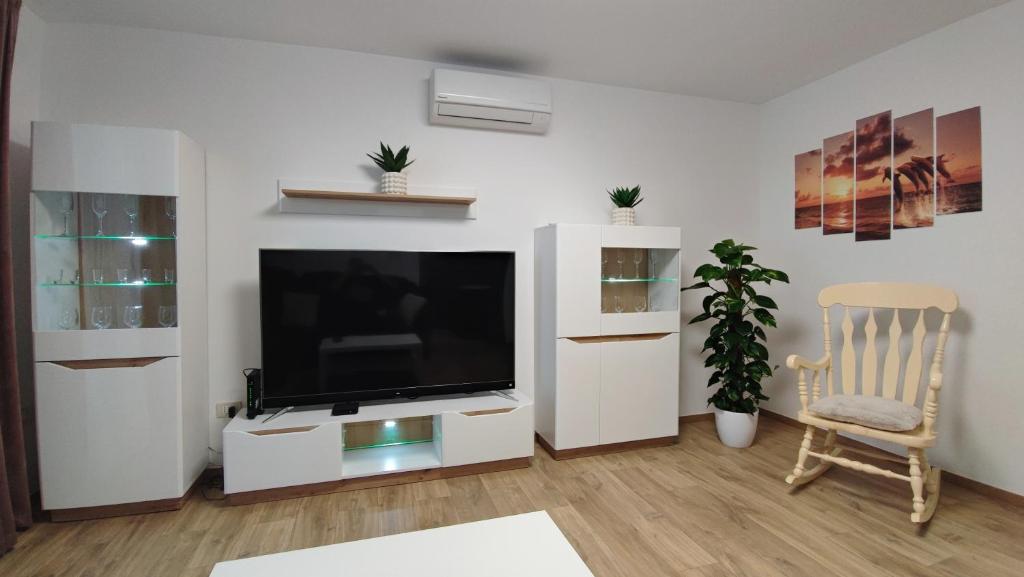 een woonkamer met een flatscreen-tv en een stoel bij Vista Capodistria in Koper