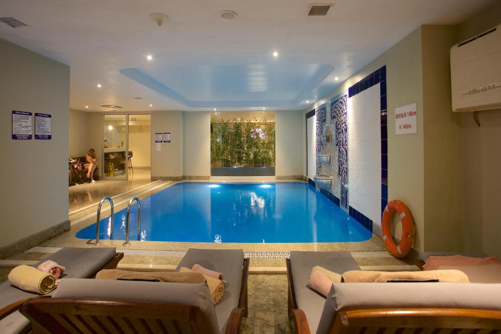 a large swimming pool in a room with chairs and a couch at Ramada By Wyndham İstanbul Taksim in Istanbul