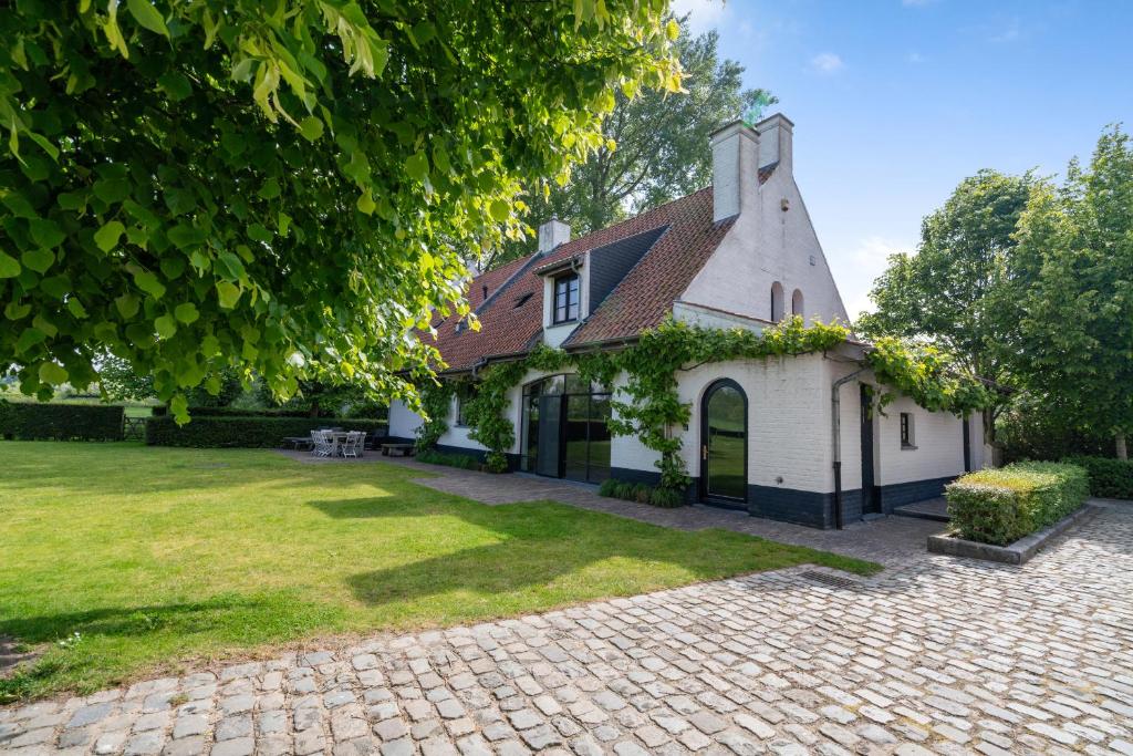 einen Blick auf ein weißes Haus mit einem Hof in der Unterkunft d'Oude Schaapskooi, de luxe vakantiehoeve in Damme in Damme