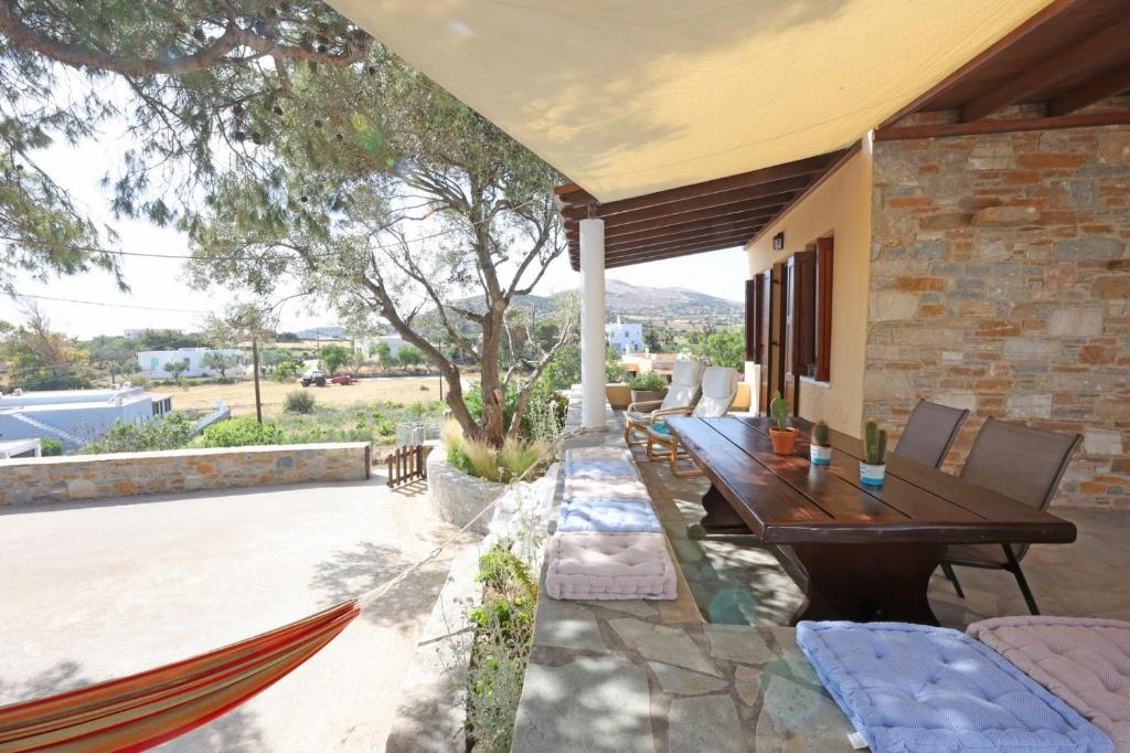 una casa con un patio con una mesa de madera y una hamaca. en Pine Cottage, Syros Island, en Firókambos