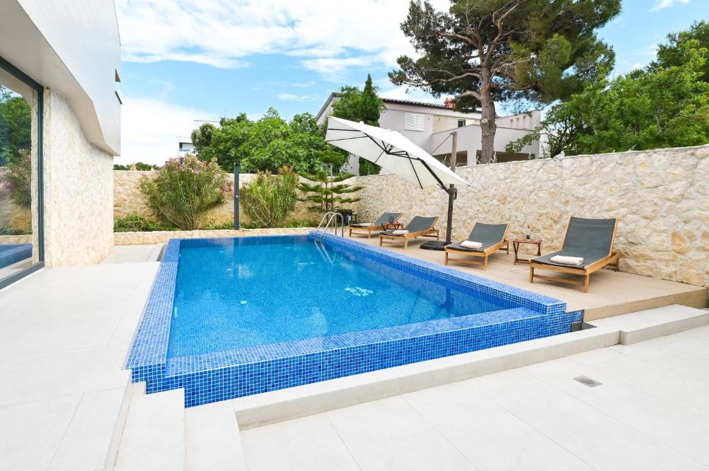 - une piscine avec un parasol à côté d'une maison dans l'établissement Villa Cornea - Luxury Villa in a heart of Novalja, à Novalja