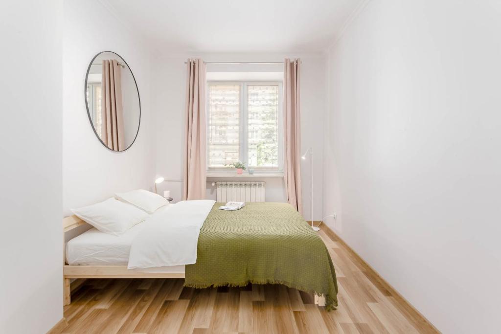 a white bedroom with a bed and a mirror at Chill Apartments Praga Waszyngtona in Warsaw