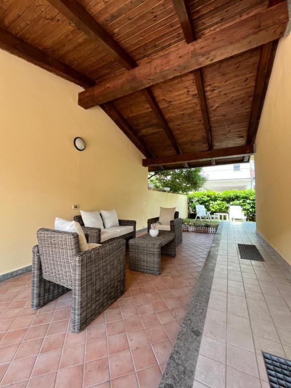 un patio al aire libre con muebles de mimbre y techo de madera. en Clò House, en Fondi