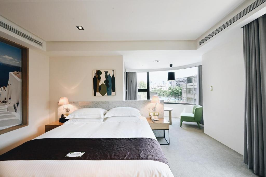 een slaapkamer met een groot bed en een groene stoel bij Gogo Hotel in Taichung