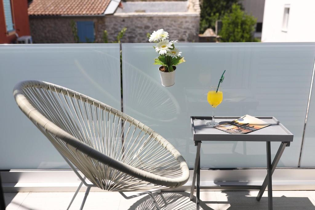 einen Stuhl und einen Tisch auf einem Balkon mit einem Getränk in der Unterkunft Holiday Home Maria one minute from -Beach in Zadar