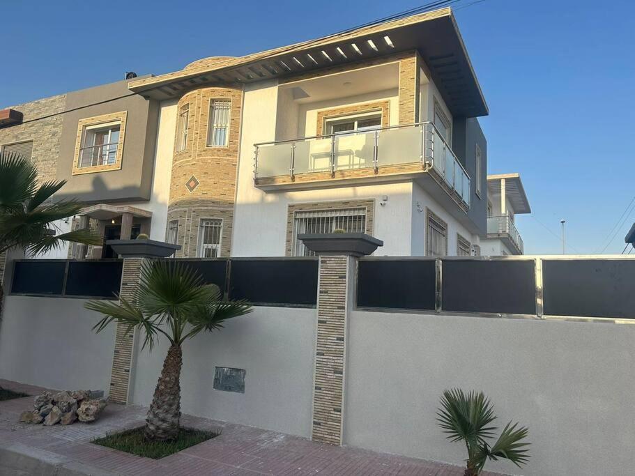 a house with a fence and a palm tree in front of it at Villa famillial avec piscine Founty in Agadir