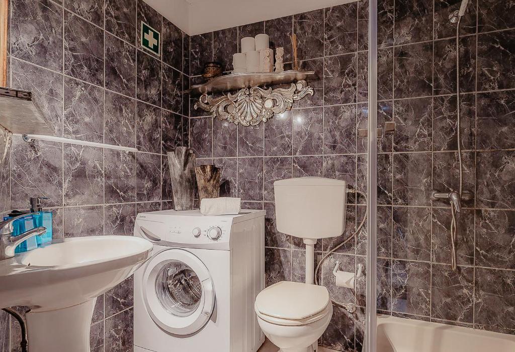 a bathroom with a toilet a sink and a washing machine at Home Santa Clara in Albufeira