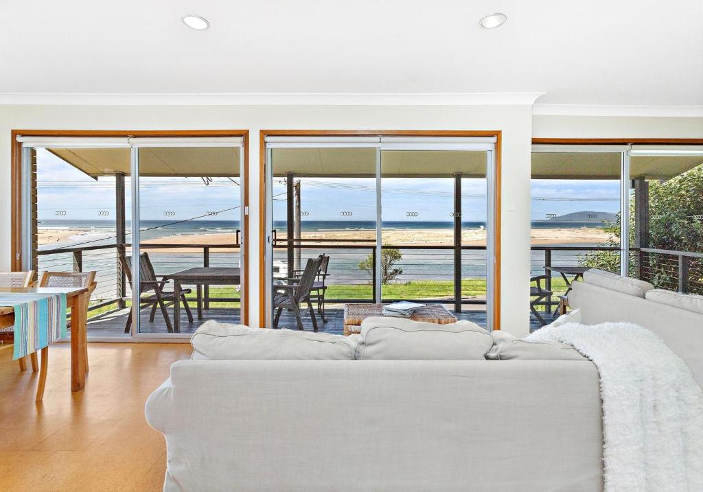 a living room with a white couch and a view of the ocean at Beachfront Gerroa in Gerroa