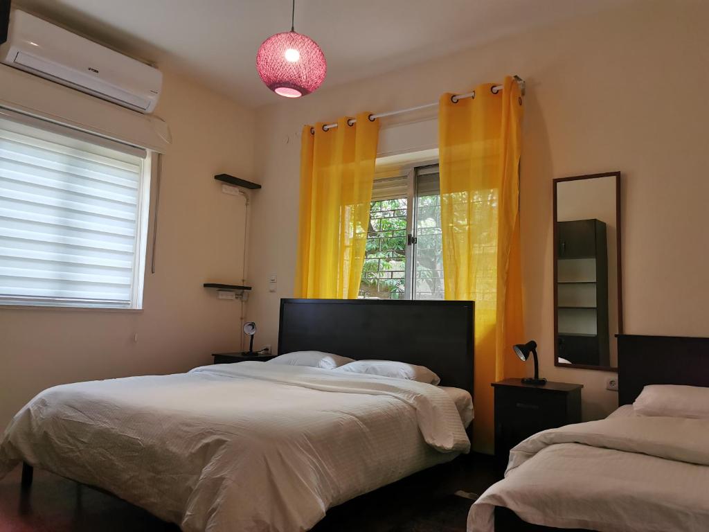 1 dormitorio con 2 camas y una ventana con cortinas amarillas en Ramallah Hostel, en Ramallah