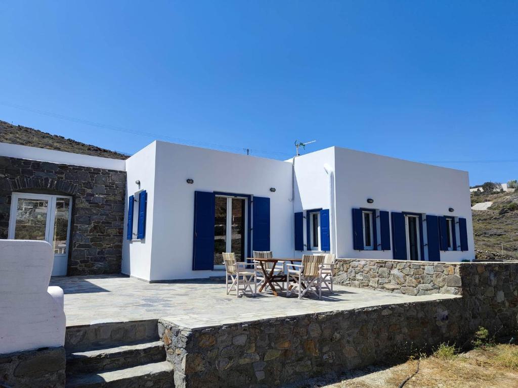 a villa with blue doors and a patio with chairs at Lighthouse View Syros in Azolimnos