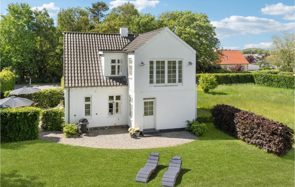 a white house in a yard with two benches at Beautiful Home In Idestrup With Wifi And 3 Bedrooms in Idestrup