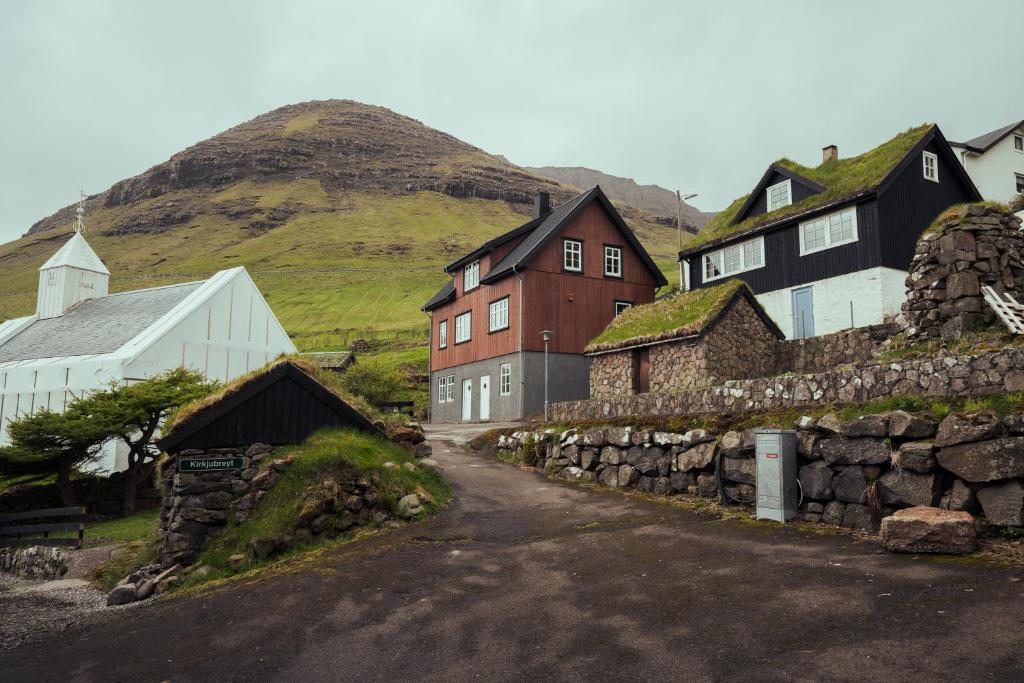 un pueblo con casas y una pared de piedra en Breathtaking View / 5-BR House / Scenic Village en Bøur