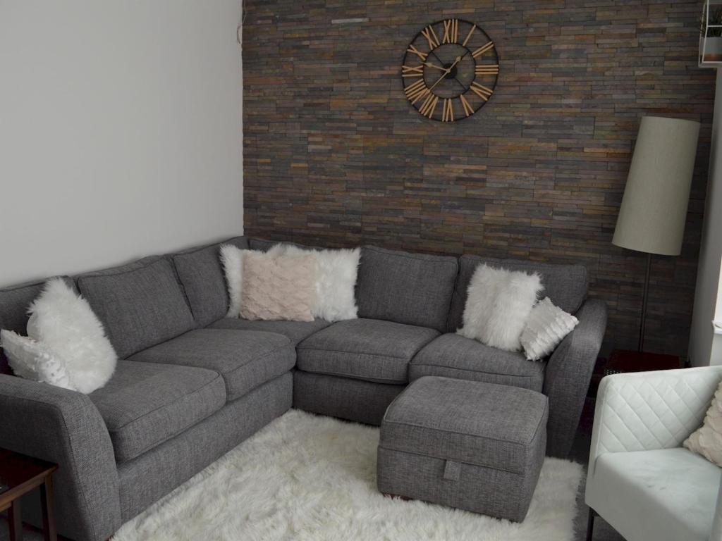 a living room with a couch and a clock on a brick wall at Pass the Keys Gorgeous Maisonette in Bournemouth