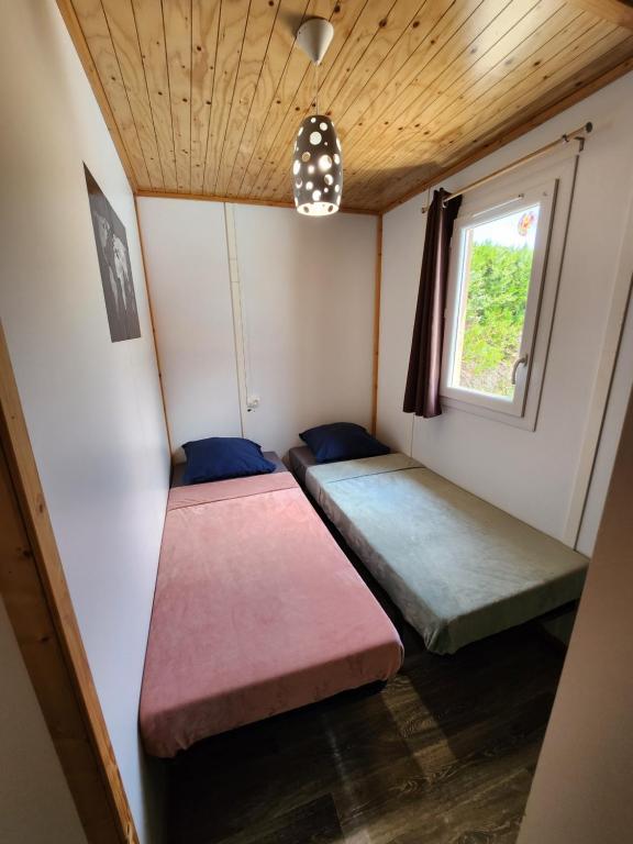 two beds in a small room with a window at Le clos de lignac in Cieux