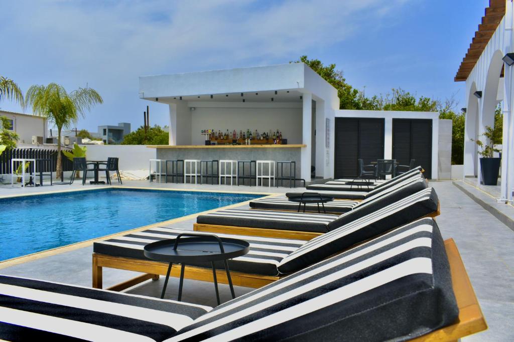 a row of chaise lounge chairs next to a swimming pool at Zoi Ayia Napa in Ayia Napa
