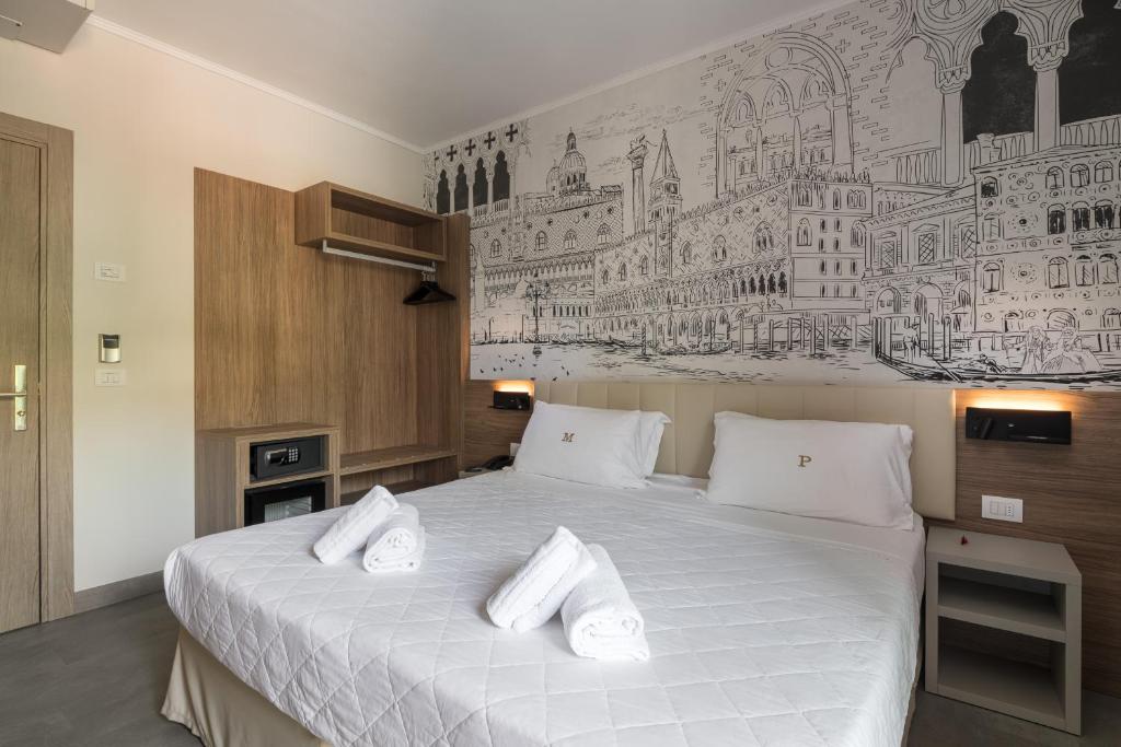 a bedroom with a large bed with white pillows at Hotel Marco Polo in Lido di Jesolo