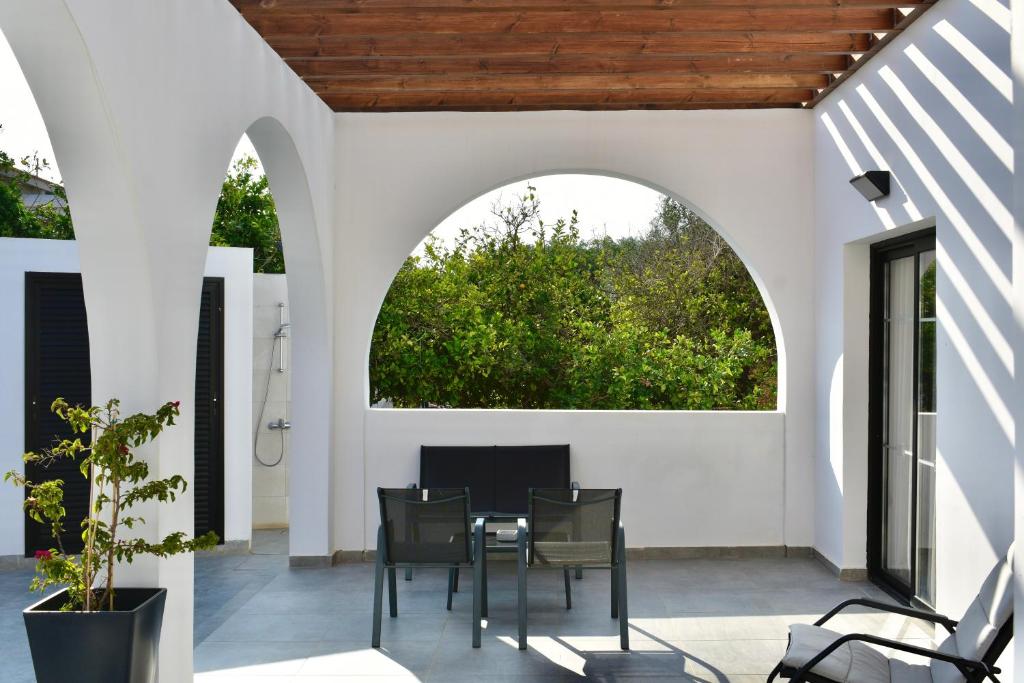 a patio with a table and chairs and an archway at Zoi Ayia Napa in Ayia Napa