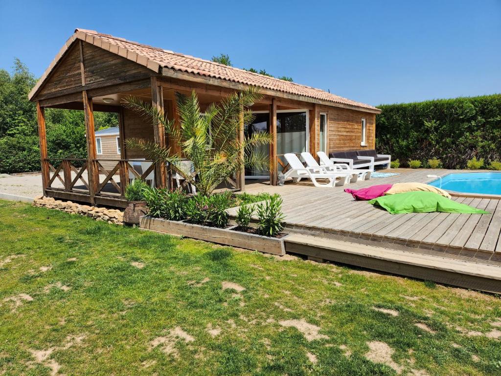 a house with a wooden deck next to a pool at Le clos de lignac in Cieux