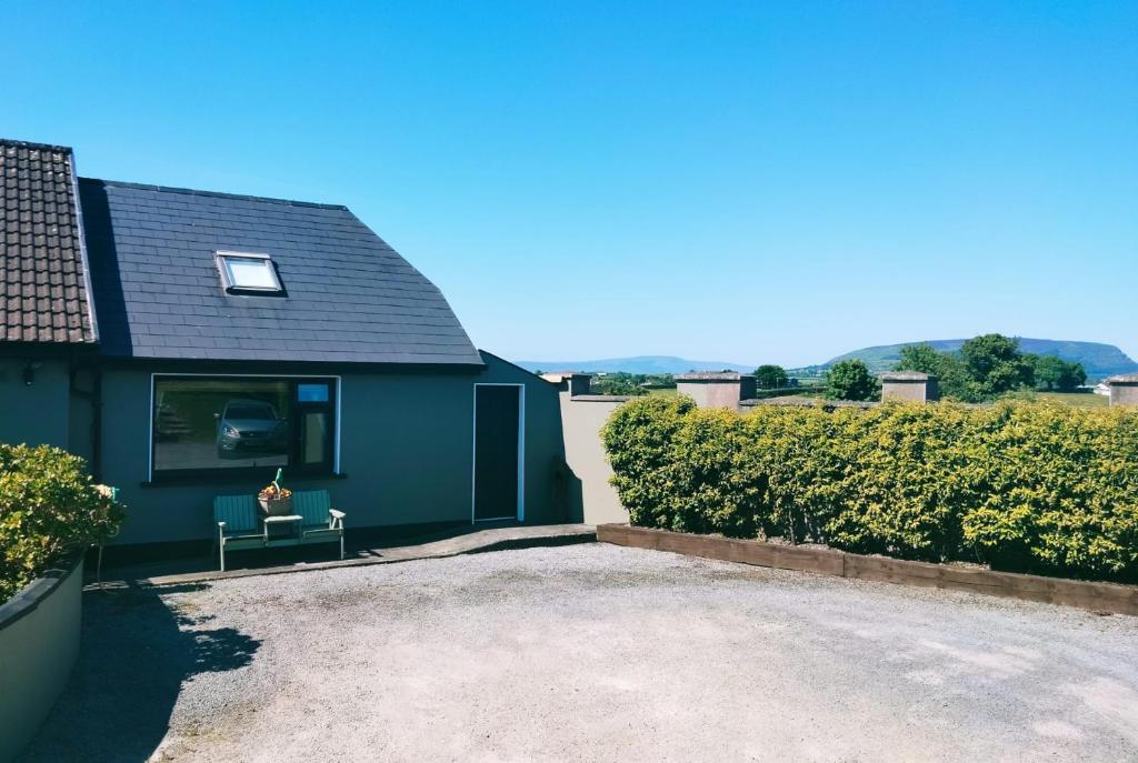 a blue house with a bench in a driveway at Benbulben View F91YN96 in Sligo