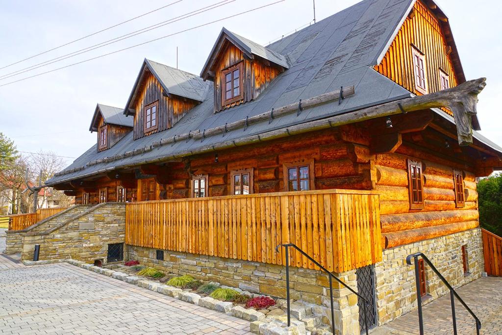 een groot houten huis met een zwart dak bij Browar POD CZARNYM KOGUTEM in Cieszyn