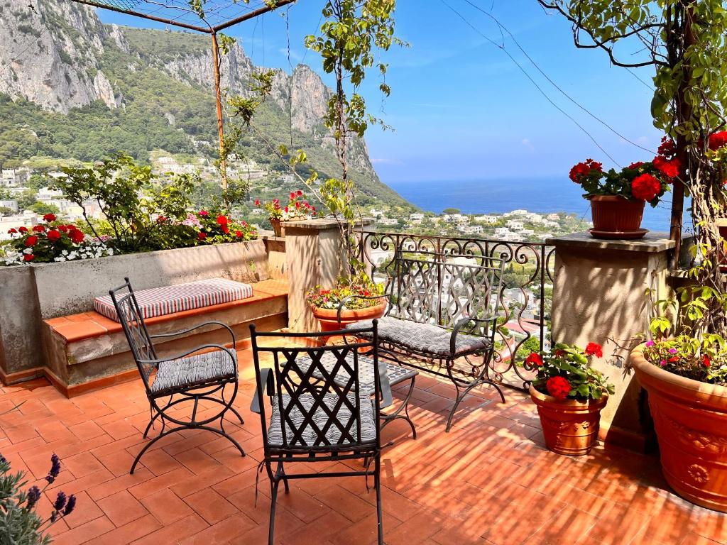 patio con sedie, tavolo e alcuni fiori di Villa Castello Apartments a Capri