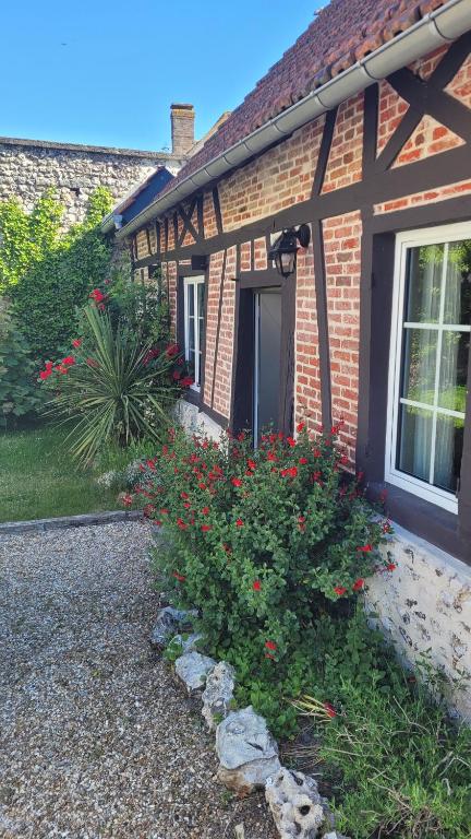 uma casa de tijolos com um arbusto de flores em frente em Le Romarande, Cottage détente avec SPA privatif em Heubécourt