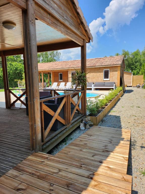 a wooden deck with a pool and a house at Le clos de lignac in Cieux
