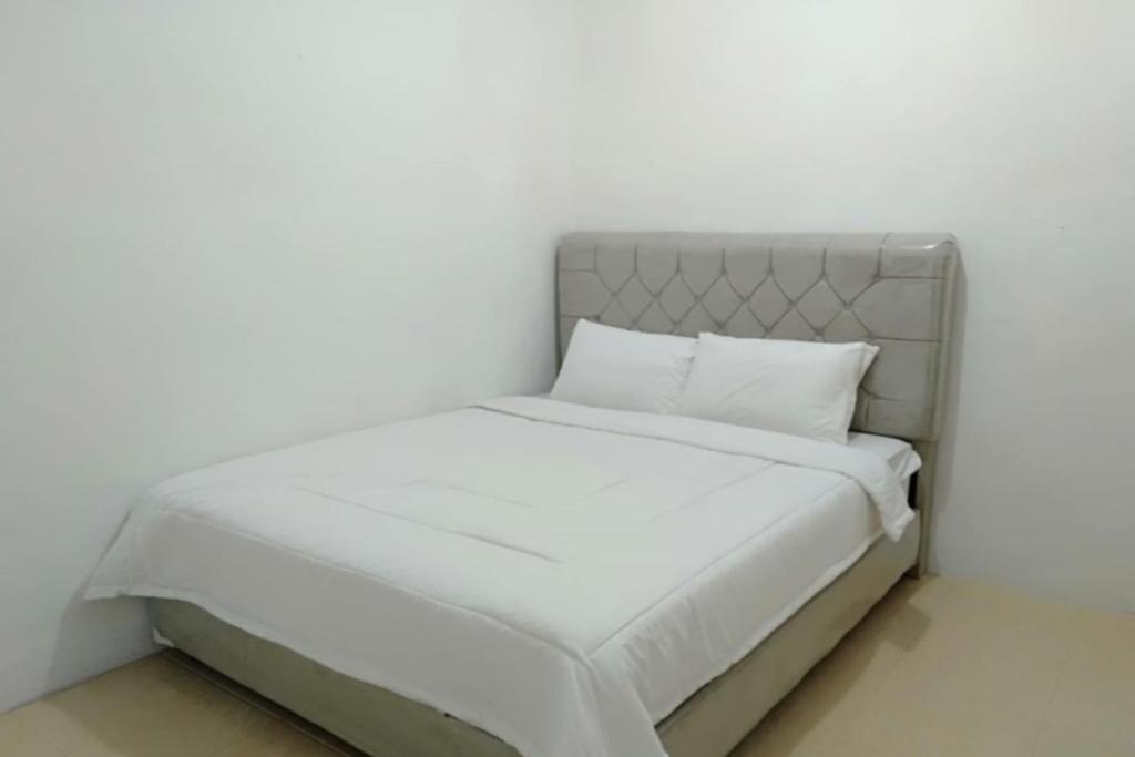 ein weißes Bett mit weißer Bettwäsche und Kissen in der Unterkunft SPOT ON 92616 As-sakinah Syariah in Medan