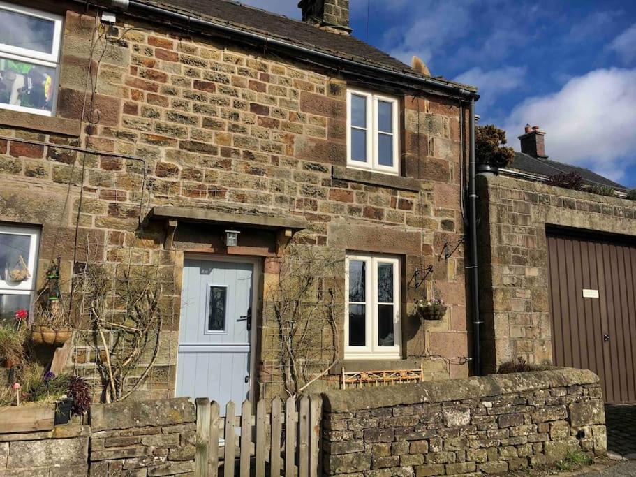 an old brick house with a white door and a fence at Honeysuckle Cottage in Longnor