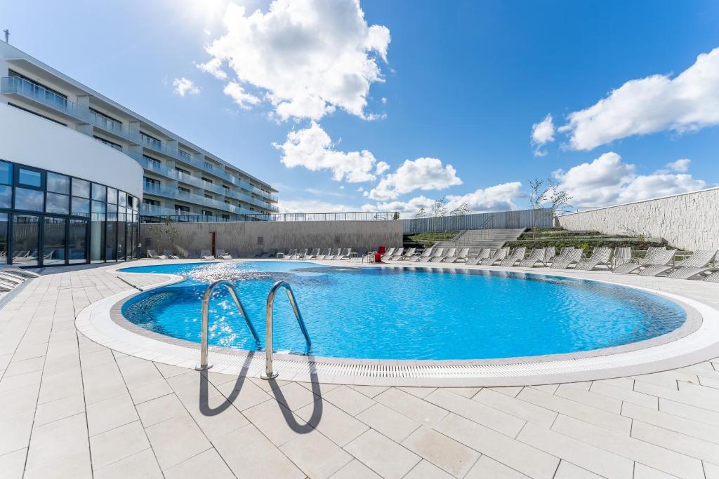 une piscine avec des chaises et un bâtiment dans l'établissement Apartament Nadmorska Przystań Polanki Aqua, à Kołobrzeg