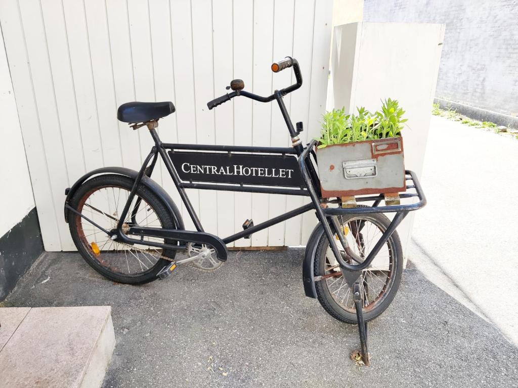 a bike parked next to a building with a plant in a basket at CentralHotellet in Køge
