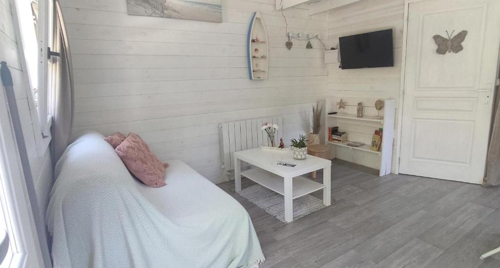 - une chambre avec un lit, une table et une télévision dans l'établissement Chalet cosy, plages à pieds. Morbihan., à Plouhinec