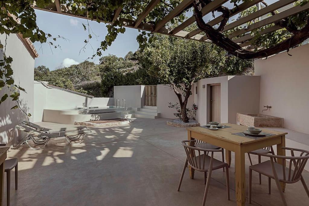a patio with a wooden table and chairs and a table and a table at Lotusland, a relaxing house at Amari Rethymno in Agia Fotini