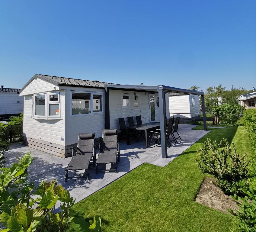 a caravan with a patio and a table and chairs at CS 71 - Vakantiepark Callassande in Callantsoog