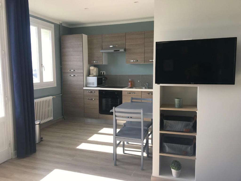 a kitchen with a table and a chair and a television at Bel appartement rénové, spacieux et lumineux in Bourg-en-Bresse