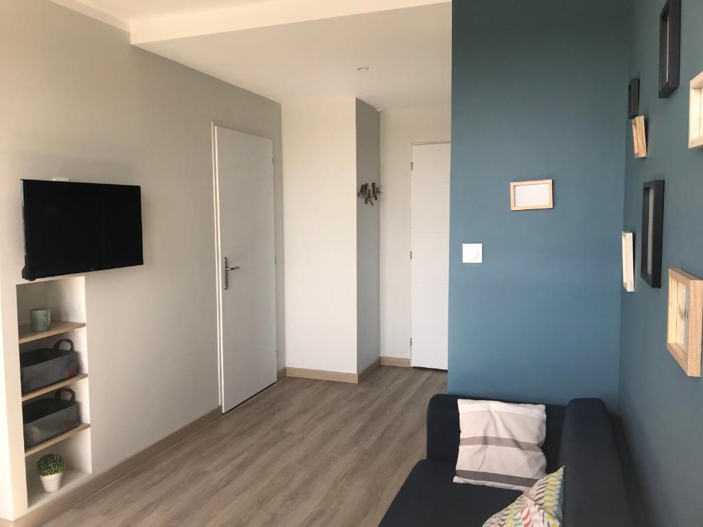 a living room with a couch and a tv on a wall at Bel appartement rénové, spacieux et lumineux in Bourg-en-Bresse