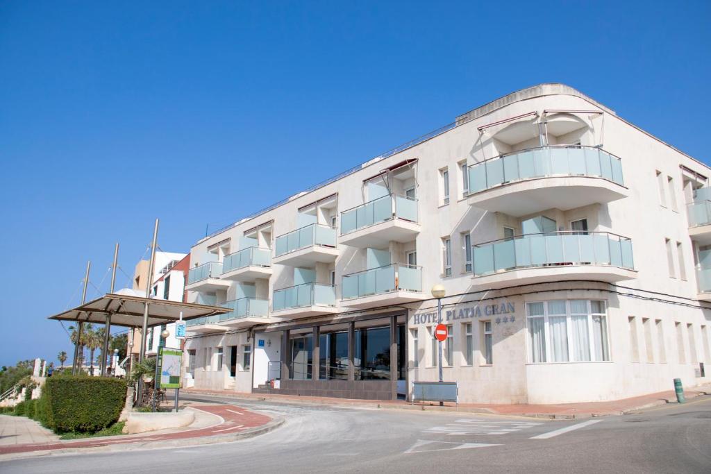 duży biały budynek na rogu ulicy w obiekcie Grupoandria Hotel Platja Gran w mieście Ciutadella