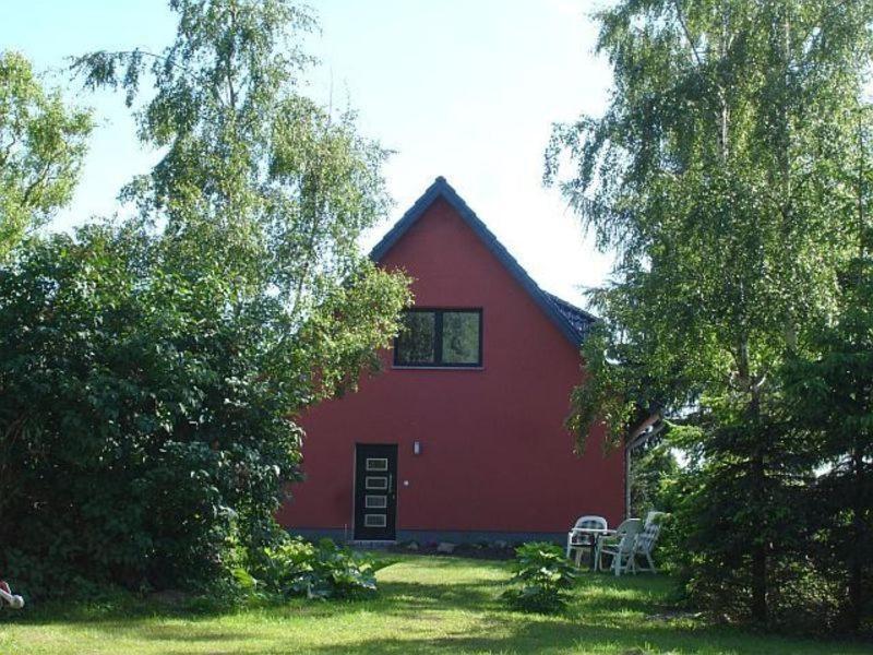 a red barn with two chairs in front of it at Rügen-Fewo 1380 in Natzevitz