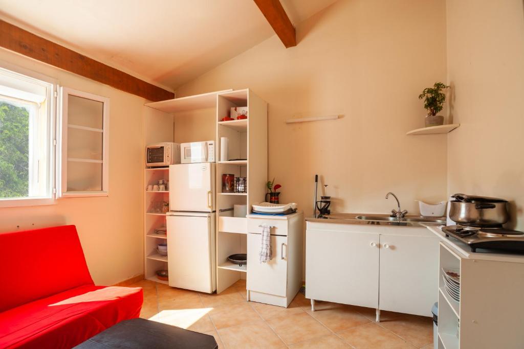 cocina con armarios blancos y sofá rojo en Les collins du sud 2, en Peyrolles-en-Provence