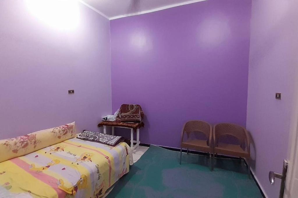 a bedroom with purple walls and a bed and chairs at Real Egypt is waiting for you in Sinnūris