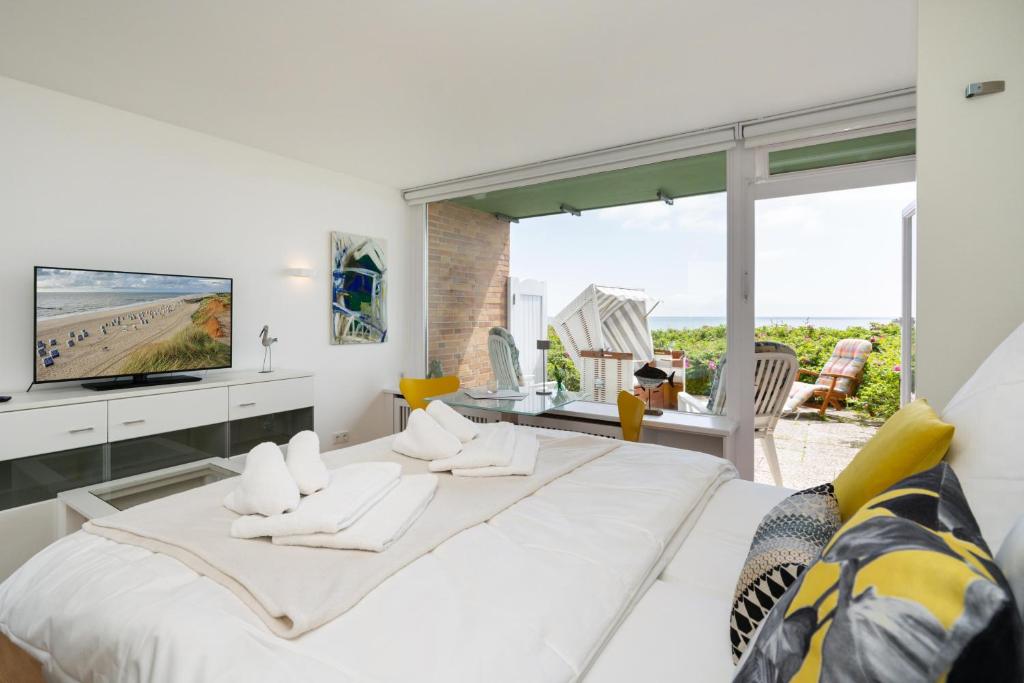 ein weißes Schlafzimmer mit einem großen Bett und einem großen Fenster in der Unterkunft Strandsonne in List
