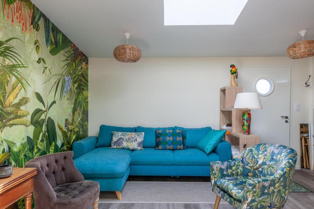 ein Wohnzimmer mit einem blauen Sofa und 2 Stühlen in der Unterkunft La Halte des Miquelots - Appt avec jardin in Vains