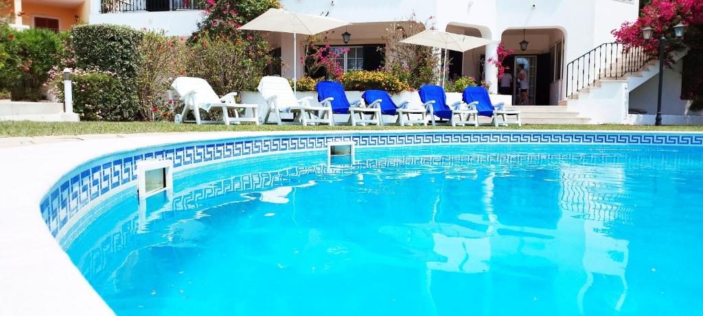 a swimming pool with blue chairs and a house at Sweet Home Lux Villa Vau in Portimão