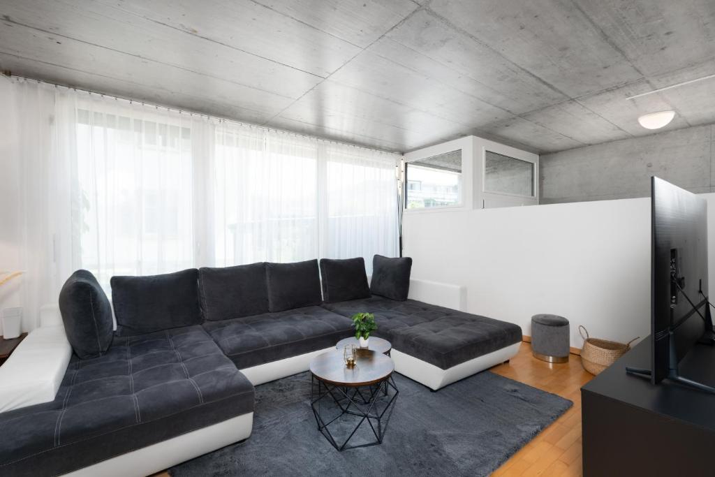 sala de estar con sofá negro y mesa en Urban Cube mit Sauna, en Thun