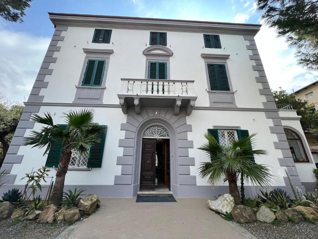 un edificio blanco con balcón y 2 palmeras en Villa Giulietta Hotel en Castiglioncello